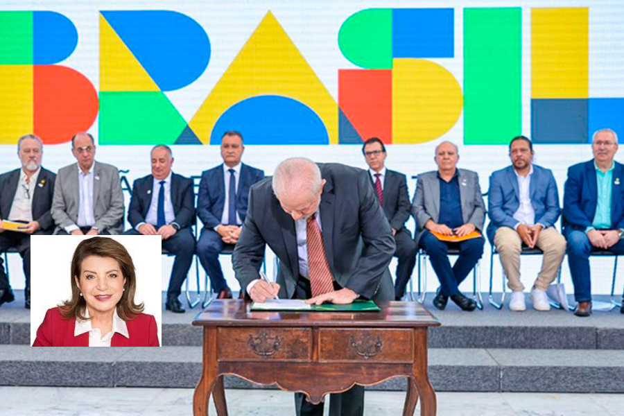 Presidente Lula curva-se para assinar decretos, enquanto, no palco, dirigentes de centrais sindicais, perfilados e sentados o observam. No destaque, foto da deputada estadual Professora Bebel (PT).
