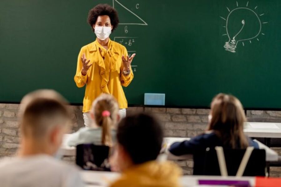 Professora de máscara em sala de aula