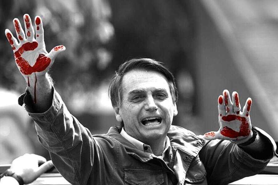 Ilustração sob foto de Bolsonaro que ergue os dois braços e mostra as palmas das mãos sujas de sangue.