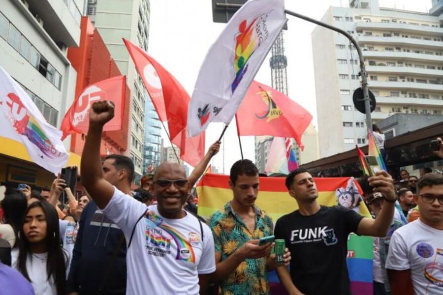Walmir Siqueira, no primeiro plano, ergue o braço, em meio à manifestação LGBTQIA+