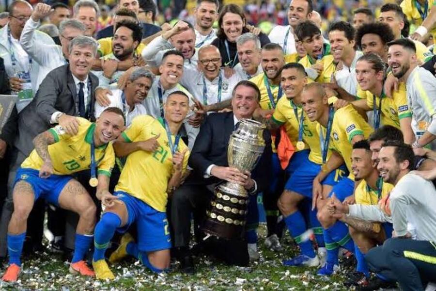 Bolsonaro segura o troféu da Copa América junto à Seleção Brasileira