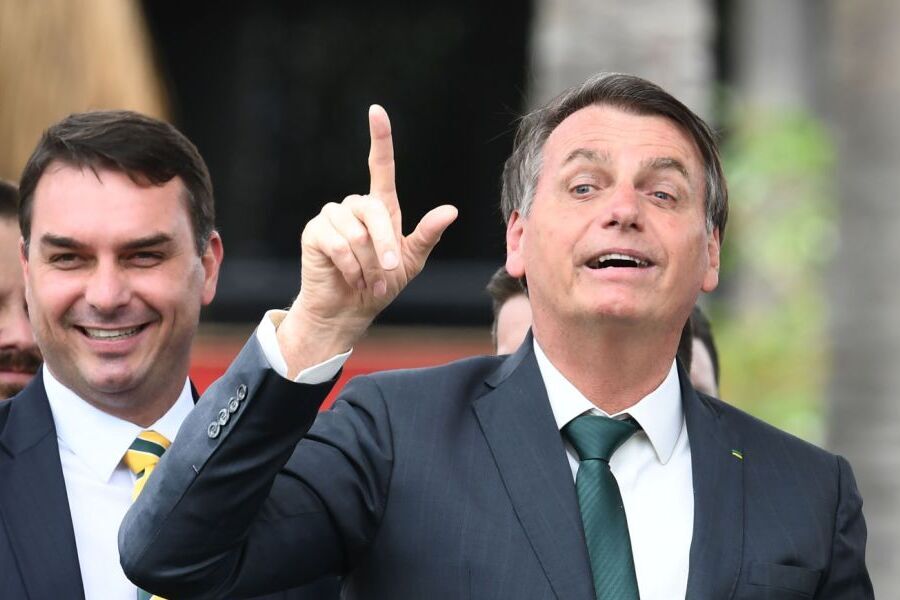 Foto do senador Flávio Bolsonaro e do presidente Jair Bolsonaro que faz arminha apontado para cima