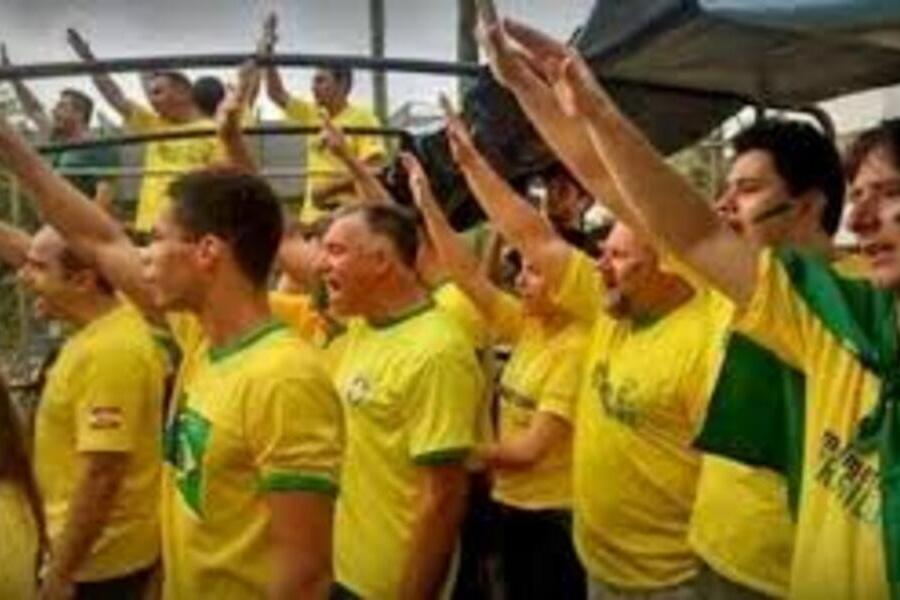 Pessoas vestindo camisetas da Seleção Brasileira erguem o braço imitando a saudação nazista