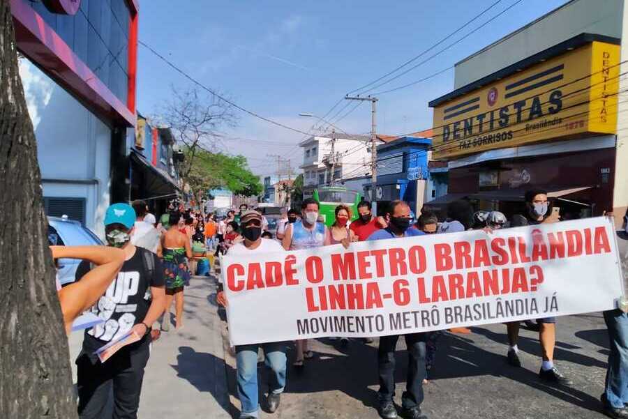 Um grupo de pessoas portam faixas pedindo a retomada das obras do Metro Brasilândia
