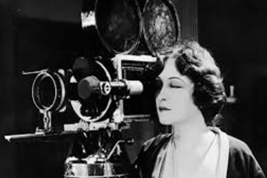 Foto muito antiga de uma mulher operando uma câmera de cinema