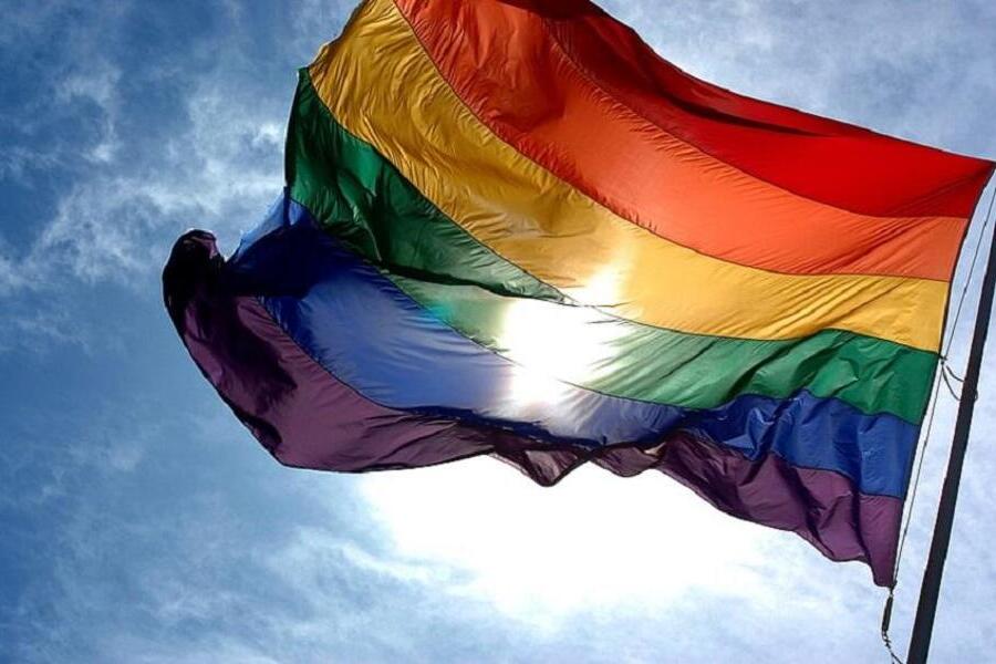 Foto da bandeira LGBTQIAP+ tremulando 