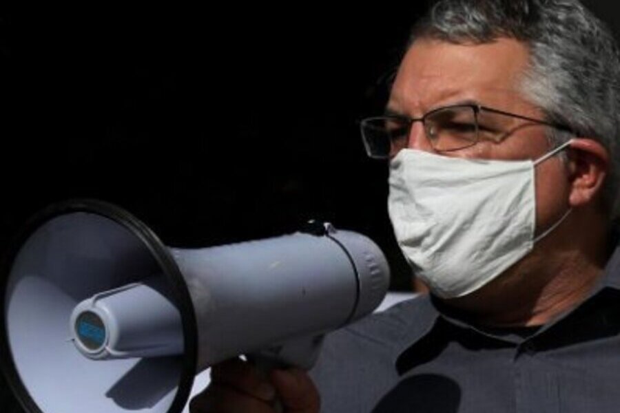Foto do deputado Alexandre Padilha falando de máscara ao megafone