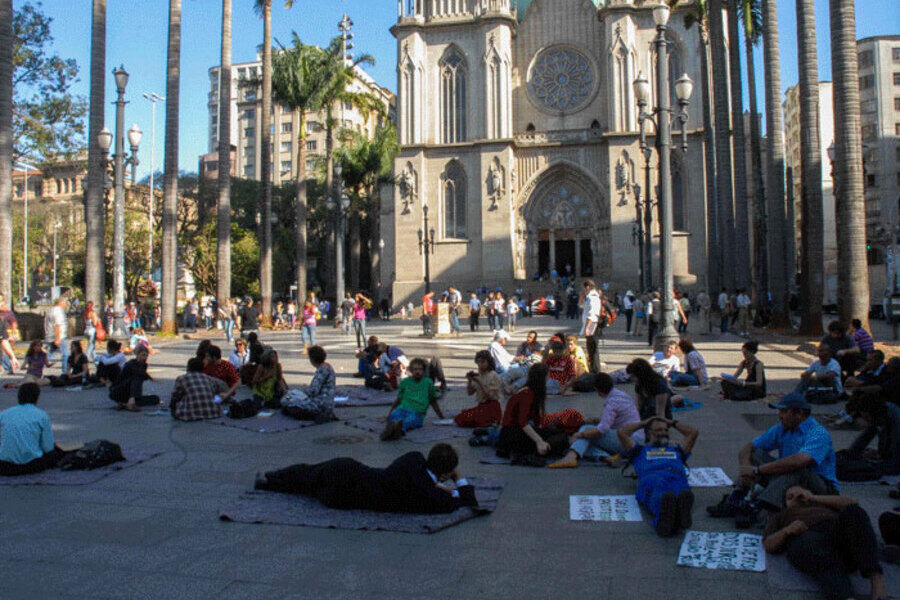 Dezenas de pessoas, moradores de rua, sentados no chão da Praça da Sé