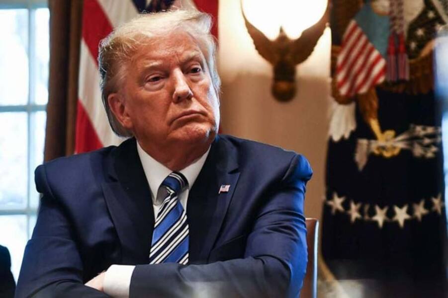 Foto de Donald Trump com braços cruzados, sentado em sua mesa na Casa Branca e com cara de poucos amigos