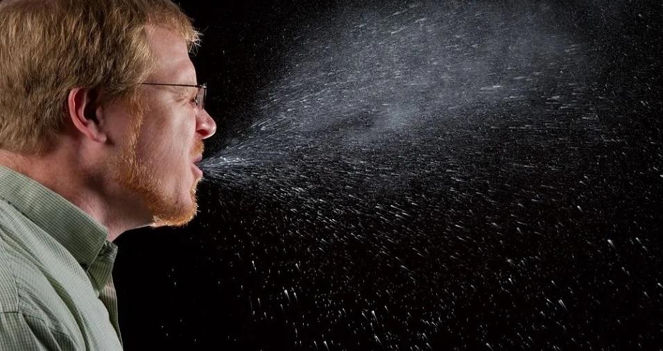 foto de um senhor espirrando e saindo várias gotículas