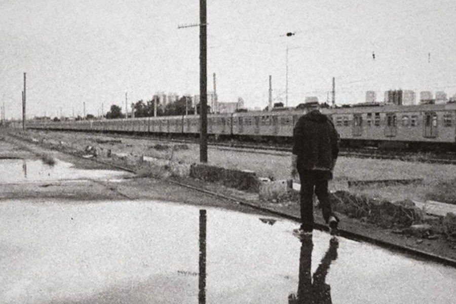 Cena do filme de Hector Babenco que mostra uma pessoa andando sozinha ao lado de uma composição de trem.