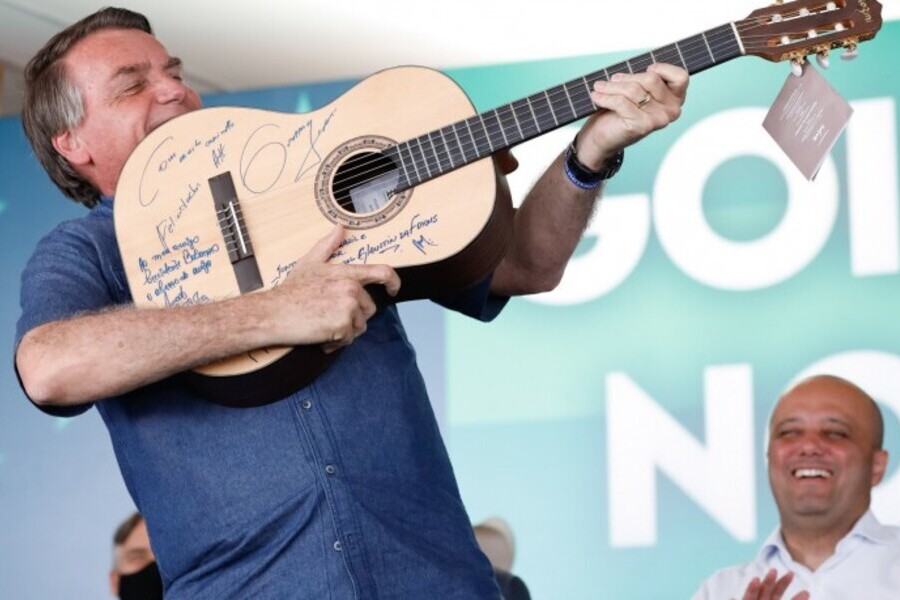 Bolsonaro faz de um violão como se fosse uma arma e o aponta para alguém