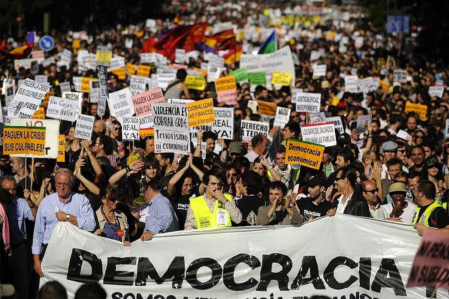 Multidão manifesta-se em defesa da Democracia. Na foto, uma grande faixa é estendida em frente à manifestação com a inscrição: Democracia