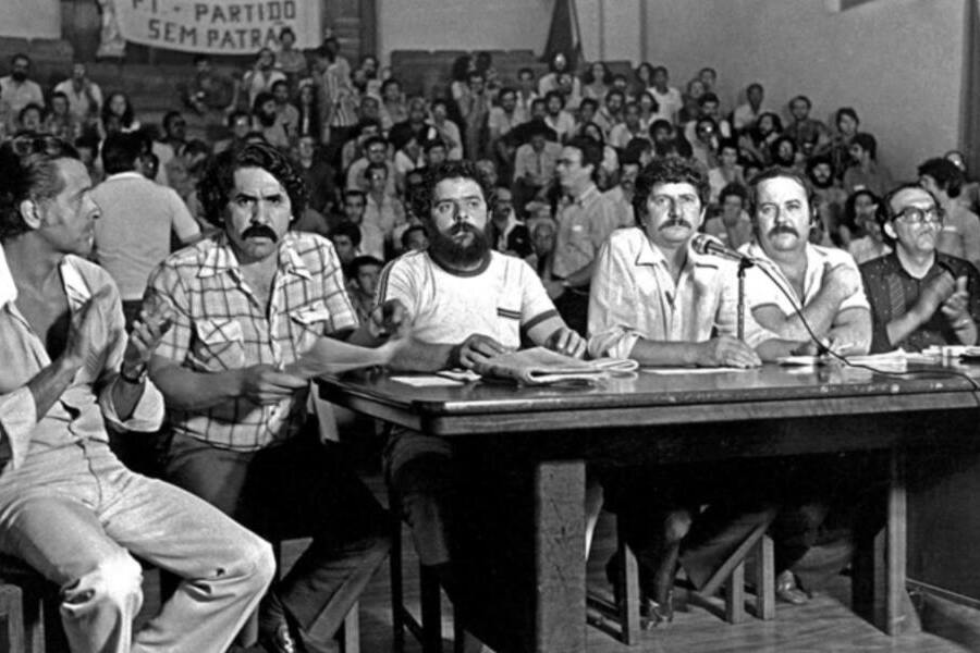 Ato de fundação do PT, no Colégio Sion, em São Paulo. Na mesa estão Lula, Olívio Dutra e Jacó Bittar, entre outros. Ao fundo, os participantes do evento.