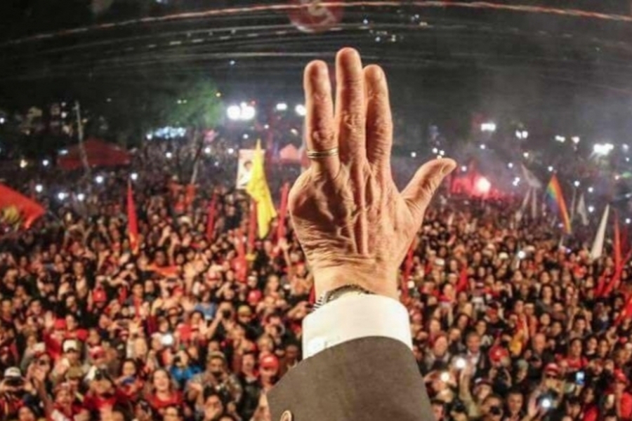 Foto do braço estendido de Lula em que se vê apenas sua mão e, ao fundo, o grande público que acompanhou seu discurso