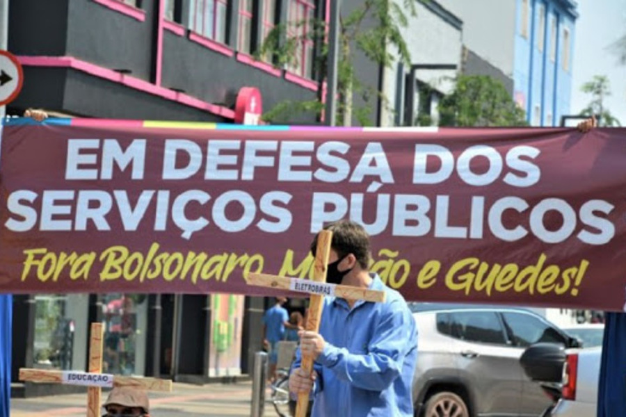 Manifestação traz um caminhão de som com enorme faixa escrita "Em Defesa dos Serviços Públicos" e logo abaixo, "fora Bolsonaro, Mourão e Guedes". Em frente, uma pessoa com máscara porta um cruz com a inscrição "Eletrobras",. Outra cruz ao lado, pregada ao chão, diz "Educação"