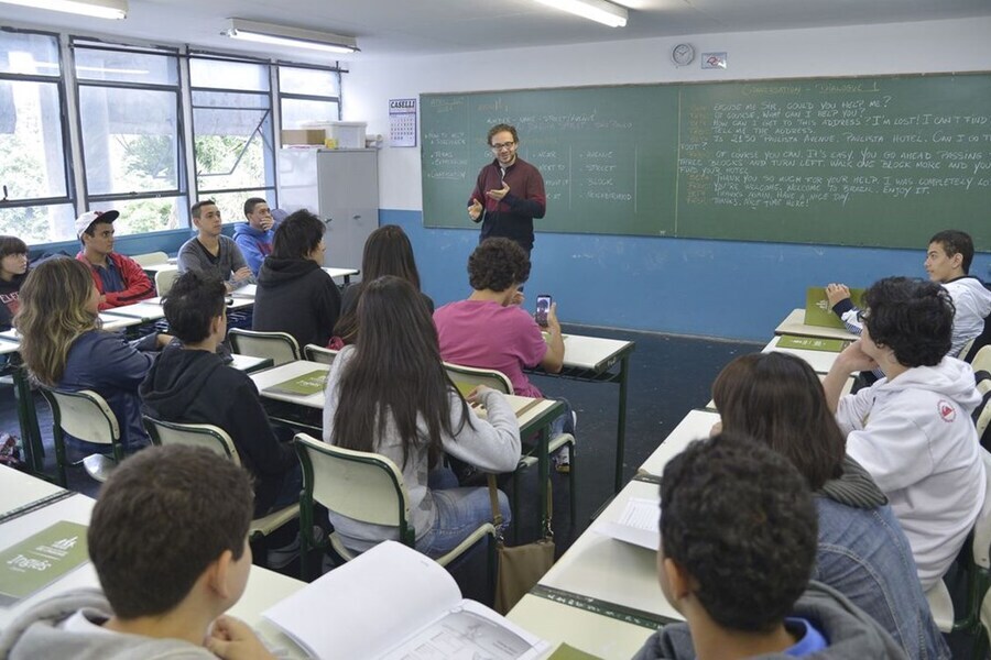 Professor dá aulas em uma sala lotada de alunos