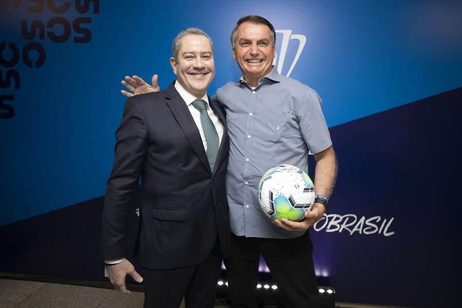 Foto de Rogêrio Caboclo e Jair Bolsonaro que segura uma bola de futebol