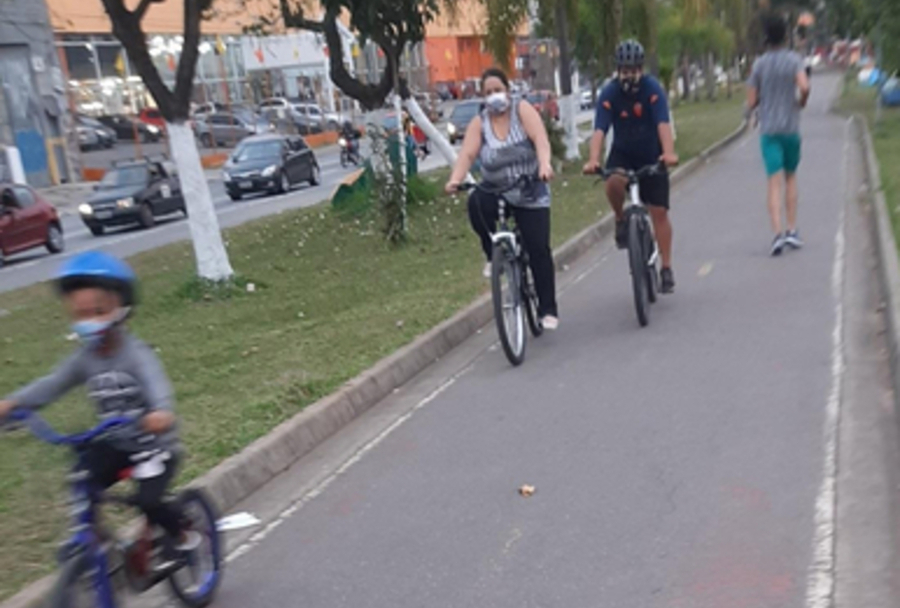 Foto de três pessoas (dois adultos e uma criança) passeando de bicicleta na ciclovia