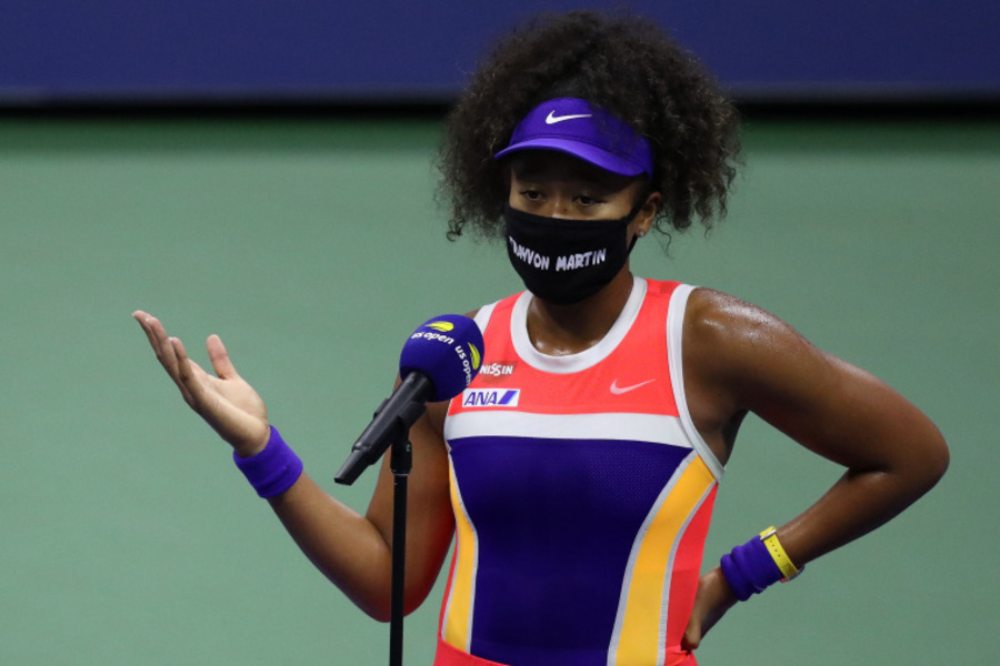A tenista Naomi Osaka falando ao microfone de máscara preta com a inscrição de Breonna Taylor, vítima da violência policial nos EUA