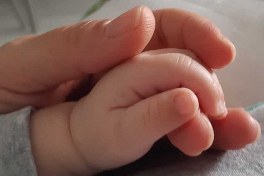 Mãe feminina afaga mão de recém-nascido