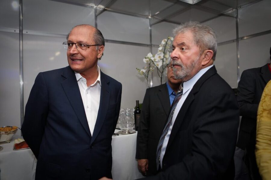 Foto de Geraldo Alckmin (à esq.) e de Lula (dir). Ambos olham para a esquerda.