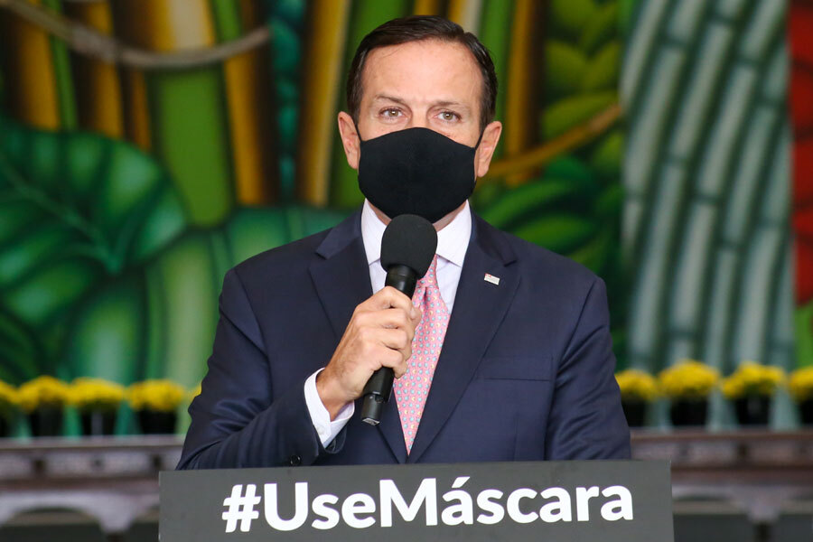 Governador de São Paulo, João Dória, de máscara, fala ao microfone