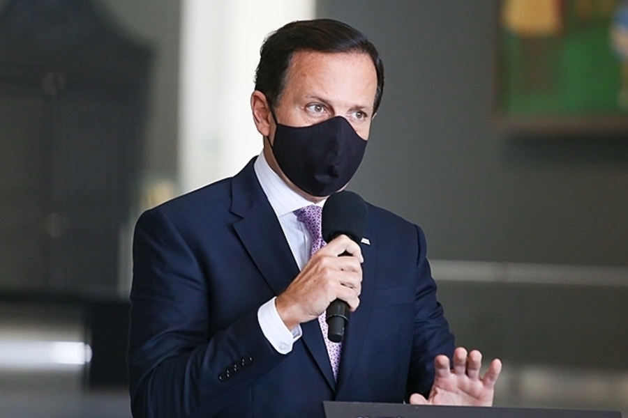 Foto do governador João Doria, de microfone na mão e de máscara, anunciando a fase vermelha