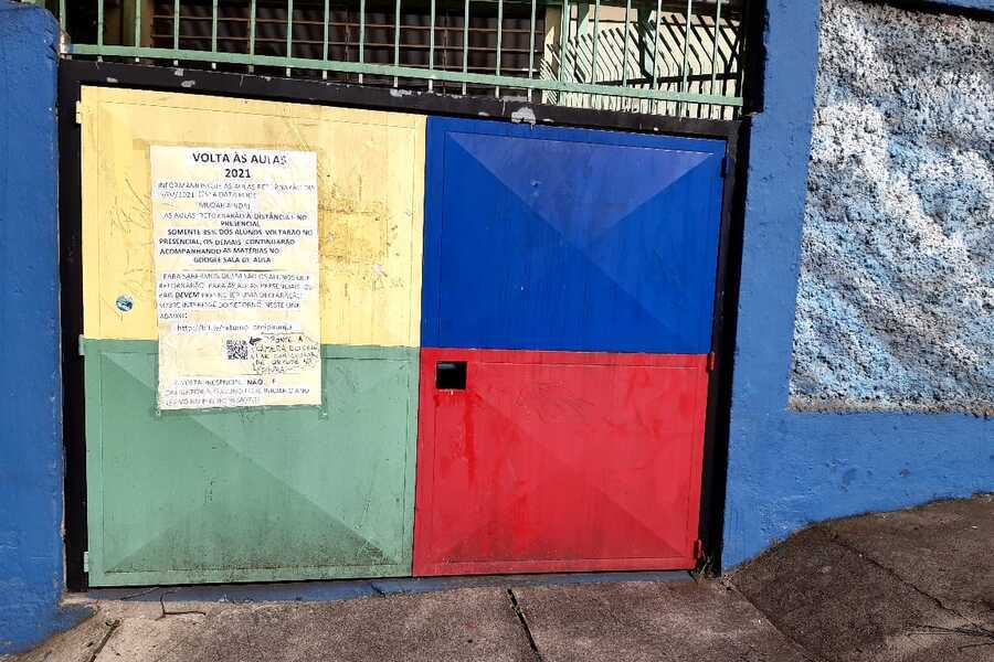 Portão da escola fechado com cartaz avisando do surto de Covid-19
