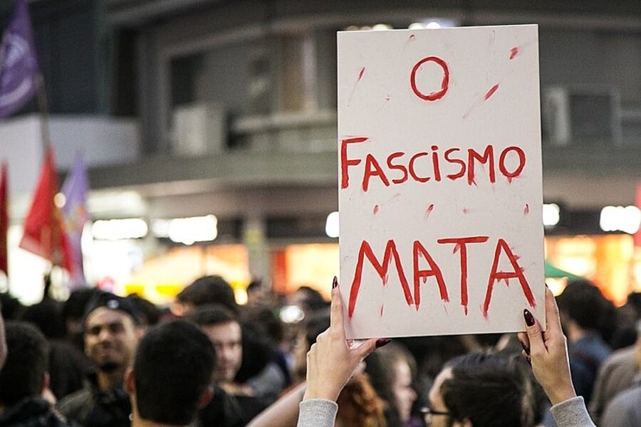 Pessoa, no meio da multidão, ergue um cartaz com a inscrição: fascismo mata