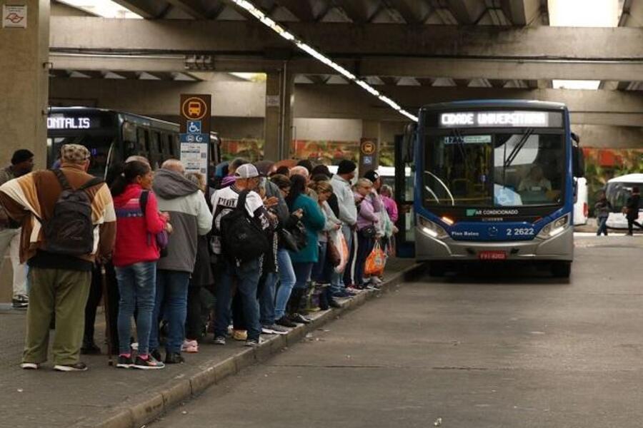 Foto de fila enorme no ponto de ônibus com idosos