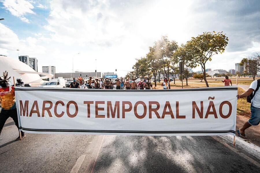 Indígenas caminham na Esplanada dos Ministérios portando faixa escrita "Marco Temporal Não"