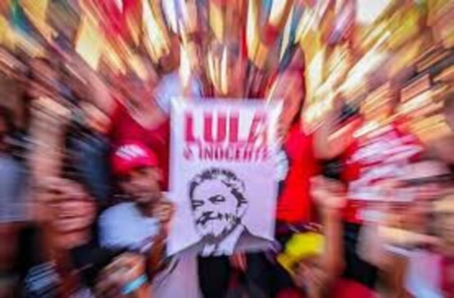 Foto de uma pessoa mostrando um cartaz com inscrito: Lula Livre, em meio a uma multidão de pessoas