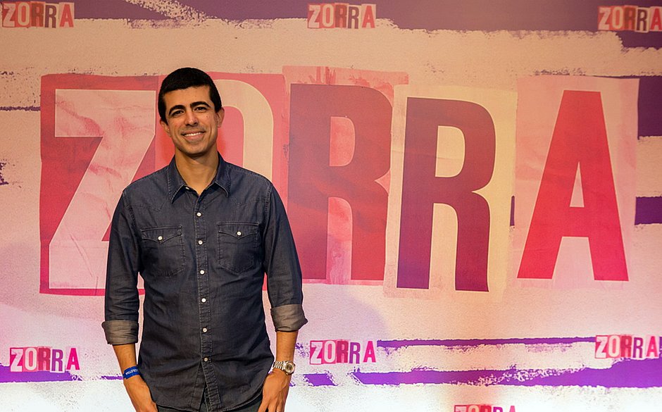 Március Melhem posa diante de uma faixa imensa escrito Zorra, programa de Humor da Globo