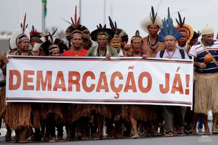 Protesto de indígenas que estendem uma grande faixa com a inscrição "Demarcação Já".