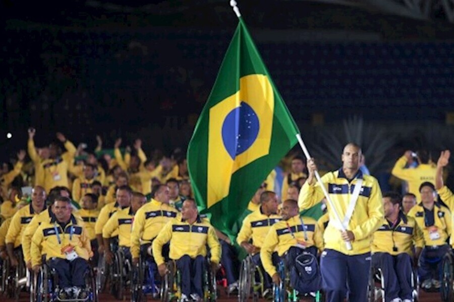 Foto da delegação paralímpica brasileira entrando no estádio. á frente o porta-bandeira carregando a bandeira brasileira