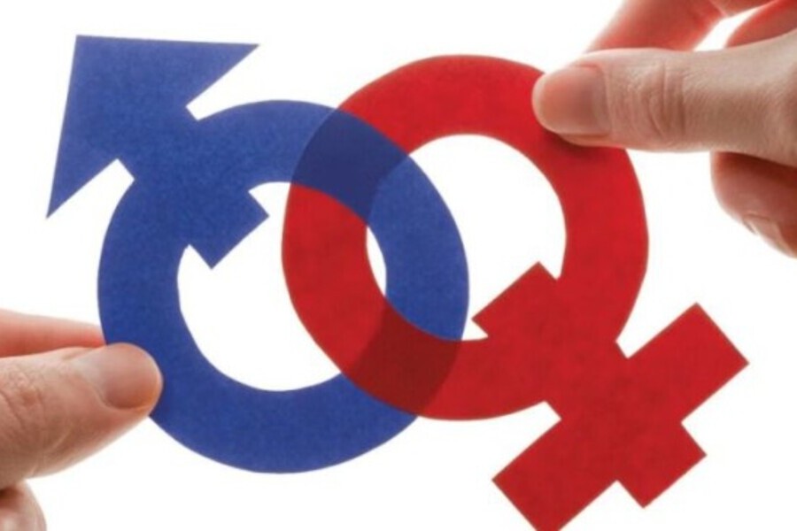Imagem de uma mão feminia segurando os símbolos dos gêneros masculino e feminino