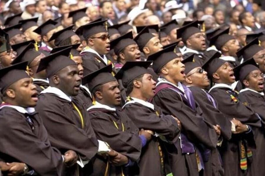 Centenas de universitários negros vestidos a caráter para a formatura dão as mãos e parecem estar falando todos ao mesmo tempo