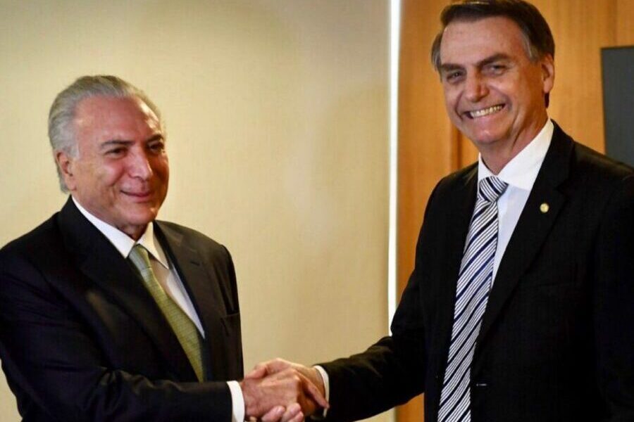 Foto de Michel Temer (dir) apertando a mão de Bolsonaro. Os dois sorriem