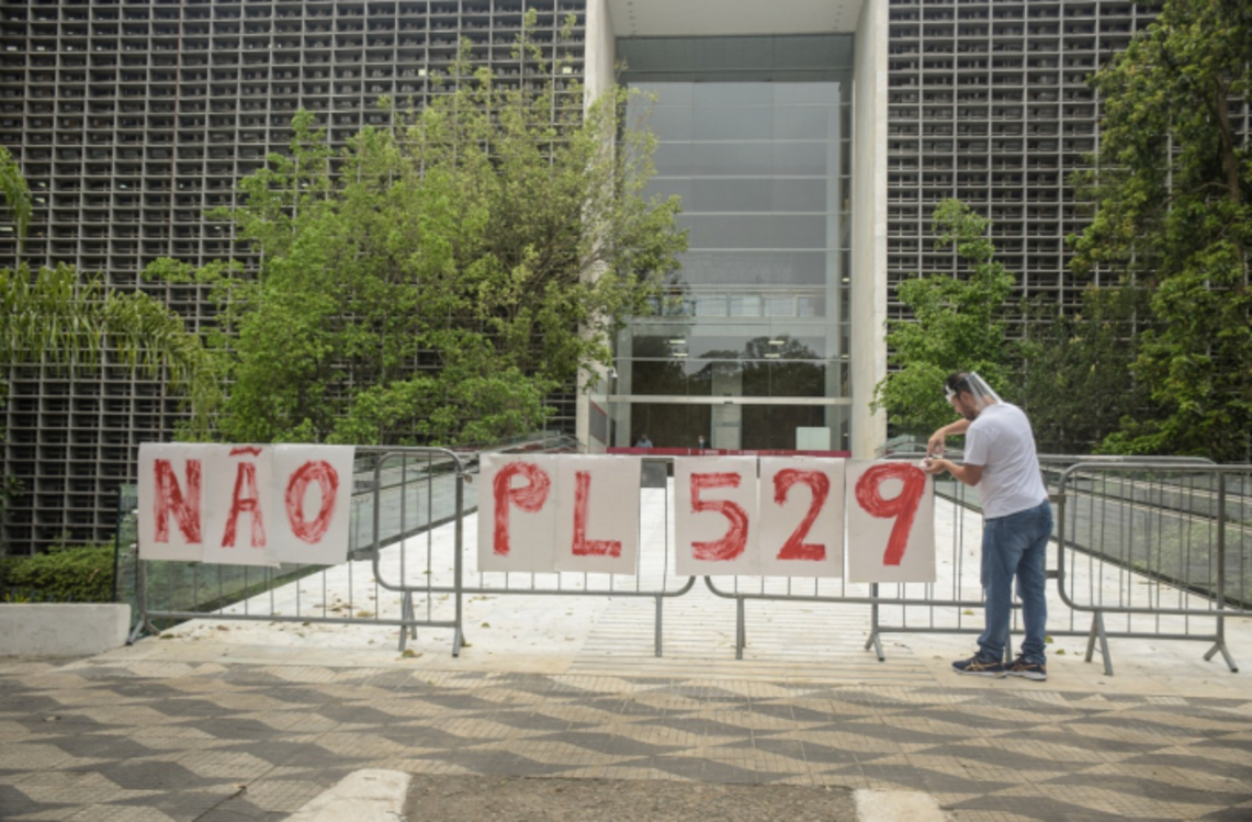 Foto de homem colocando faixa Não ao PL 529 no gradil da Alesp
