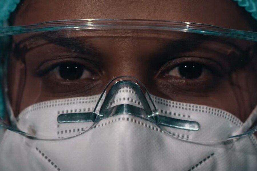 Foto em close de uma enfermeira usando máscara, óculos protetor e touca