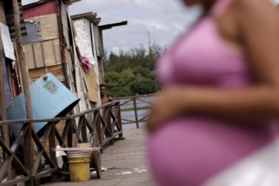 Foto de mulher grávida diante de sua casa na comunidade