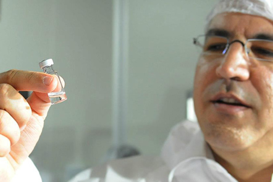 Foto do Deputado Federal e médico Alexandre Padilha observando uma ampola de vacina