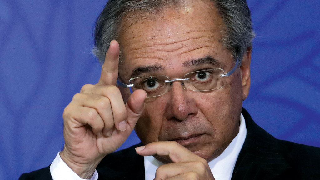 Foto do ministro Paulo Guedes em close gesticulando. Com a mão esquerda apontando pra baixo e com a direita pra cima.