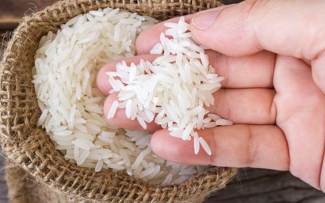 Close da mão de alguém pegando um punhado de arroz