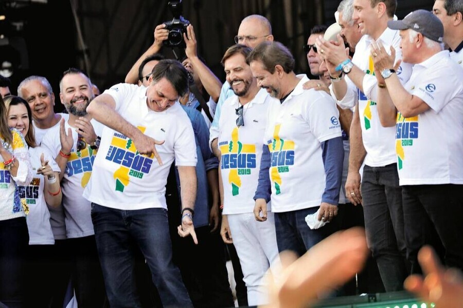 Jair Bolsonaro faz arminha com as duas mãos apontando pra baixo, simulando uma execução sumária, durante ato de evangélicos