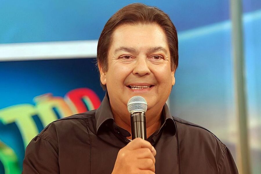 Foto do apresentador Fausto Silva sorrindo e falando ao microfone