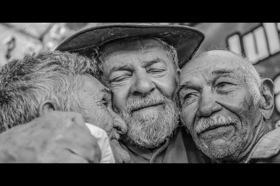 Foto de Lula abraçando um casal de idosos de forma muito carinhosa.