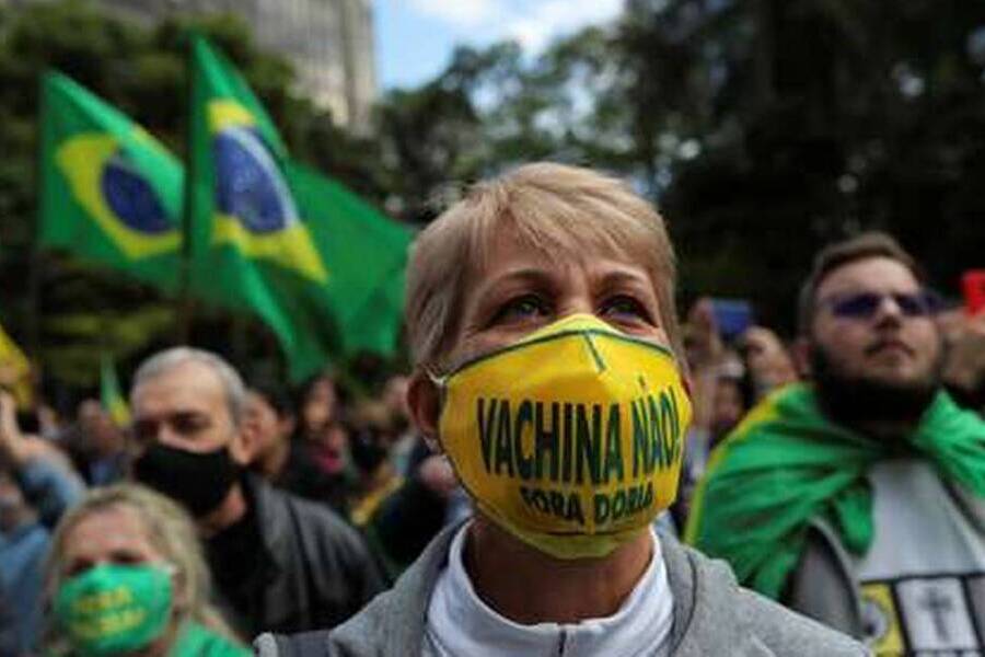 Militante bolsonarista mulher, de máscara, com a inscrição "Vacina, não".