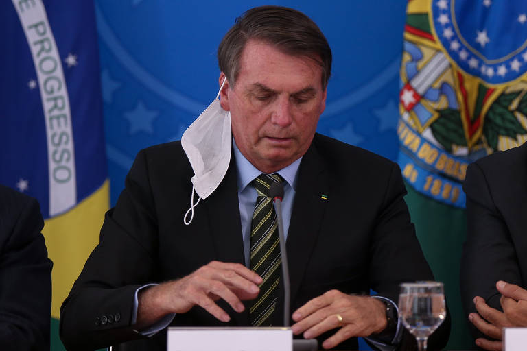 foto de Bolsonaro sentado com a máscara pendurada em sua orelha direita